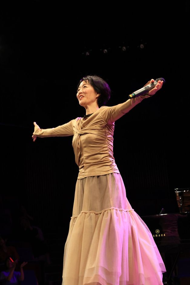 ステージで両手を広げる奥村まみ子